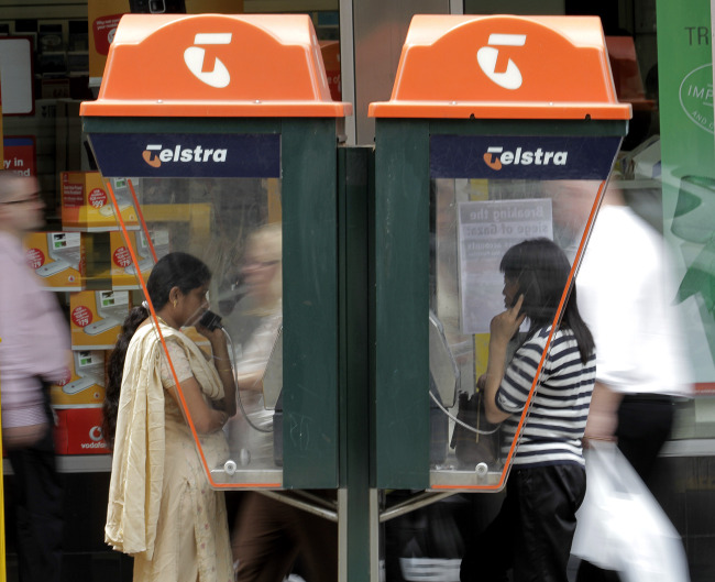 People talk on Telstra Corp. pay phones in Melbourne, Australia. (Bloomberg)