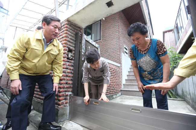 President Park Geun-hye inspects a water barrier installed at a home in western Seoul in an area commonly affected by floods on Monday accompanied by Minister of Security and Public Administration Yoo Jeong-bok (left). (Cheong Wa Dae Joint Press Corps)