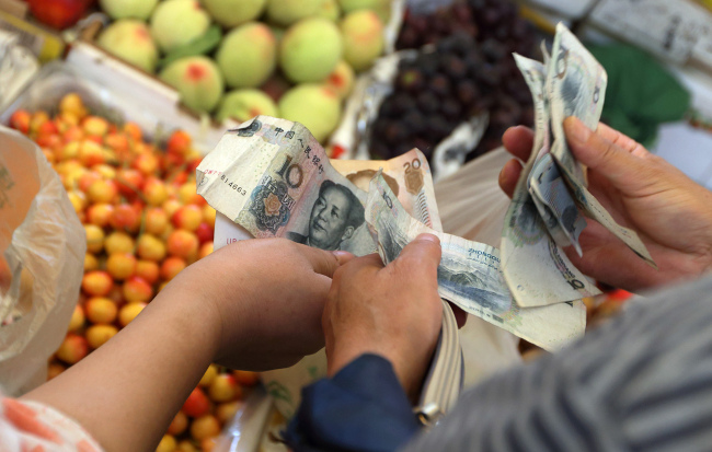 A shopper counts Chinese yuan banknotes as he shops for fruit in Shanghai. (Bloomberg)