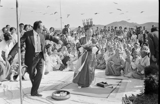 A shaman in her costume performs a ritual to show respect to the king of the sea at a seaside village in Tongyeong, South Gyeongsang Province, in the 1980s. (The National Folk Museum of Korea)