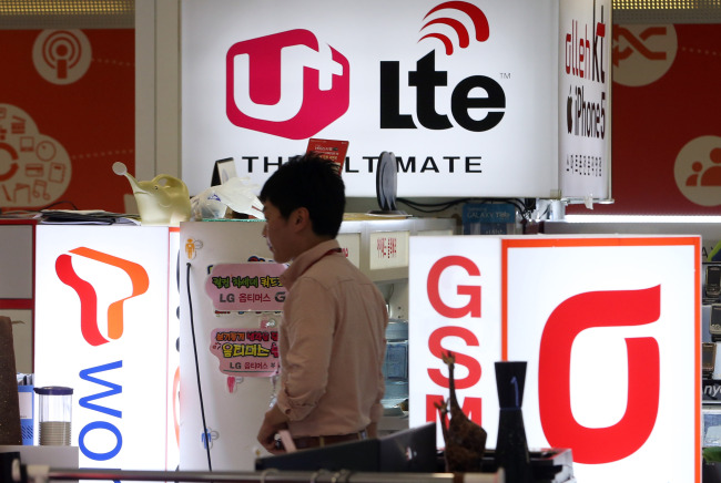 A customer walks past a shop selling mobile phones in Seoul on Thursday. (Yonhap News)