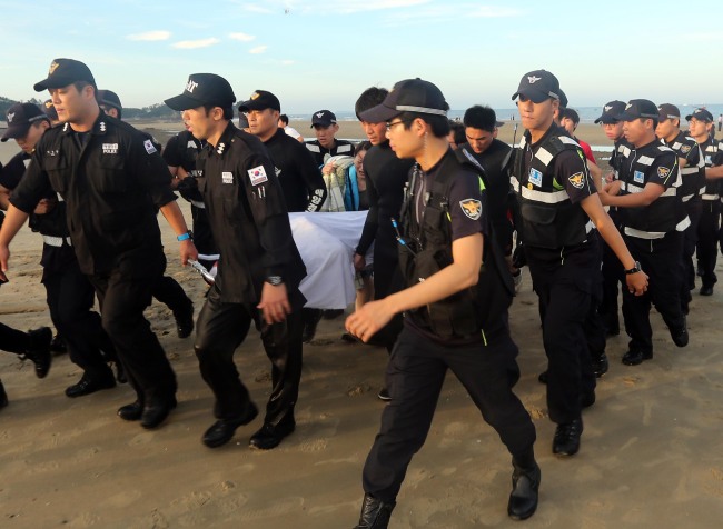 Taean Coast Guard officials carry the body of a high school student found dead near Baeksajang Beach in Taean, South Chungcheong Province, Friday. ( Yonhap News)