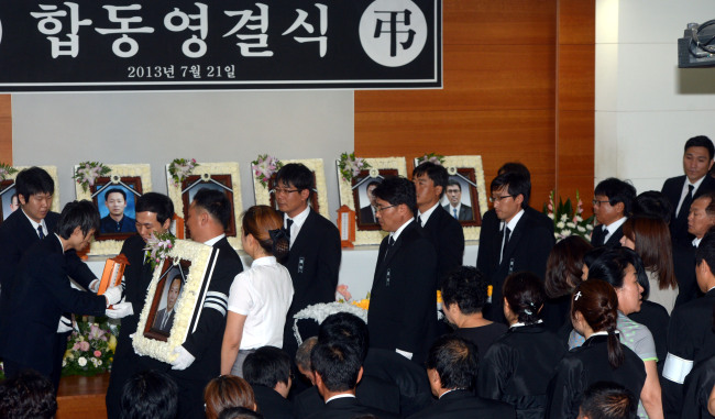 A relative carries the portrait of one of seven workers killed in a flash flood on July 15 at a construction site in southern Seoul, at a joint funeral service at the Korea University Guro Hospital in Seoul on Sunday. (Ahn Hoon/ The Korea Herald)