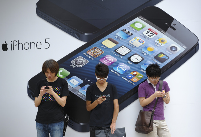 People stand outside a store advertising the iPhone 5 in Tokyo. (Bloomberg)