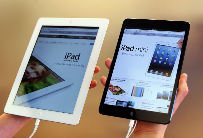 An employee displays iPad mini (right) and 4G iPad models at an Apple Inc. store in San Francisco, California. (Bloomberg)