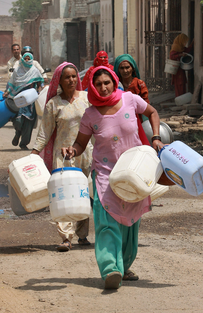 Residents carry plastic containers to collect water from a government water supply tank in New Delhi. (Bloomberg)