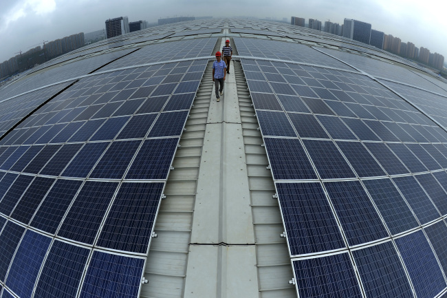 Two men walk on the roof of Hangzhou East Railway Station, which is covered by solar panels. (AP-Yonhap News)