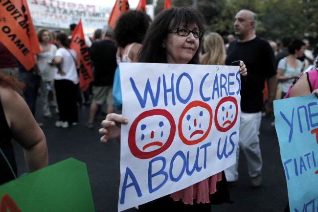 A protesting civil servant holds a banner during a rally in central Syntagma Square outside the Greek Parliament in Athens on July 15. (AP-Yonhap News)