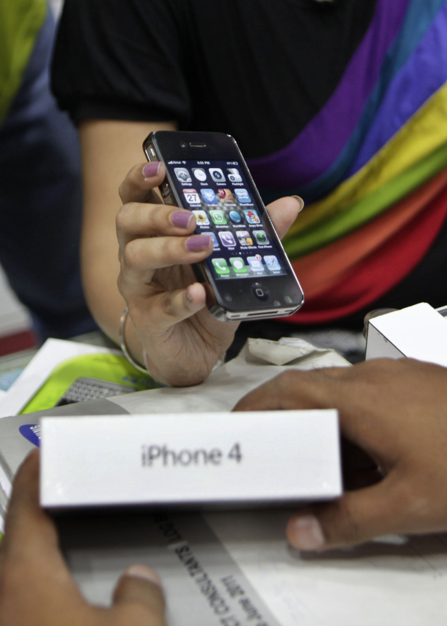 A salesperson at a mobile phone shop displays an Apple iPhone 4 to a customer in New Delhi. (AP-Yonhap News)