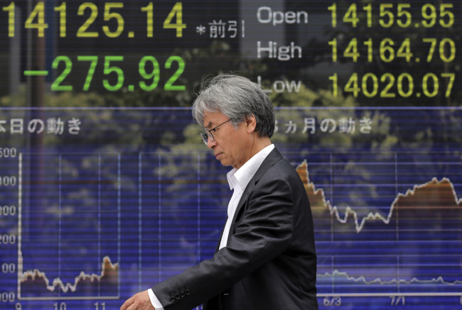 A man walks by an electronic stock board in Tokyo on Wednesday. (AP-Yonhap News)