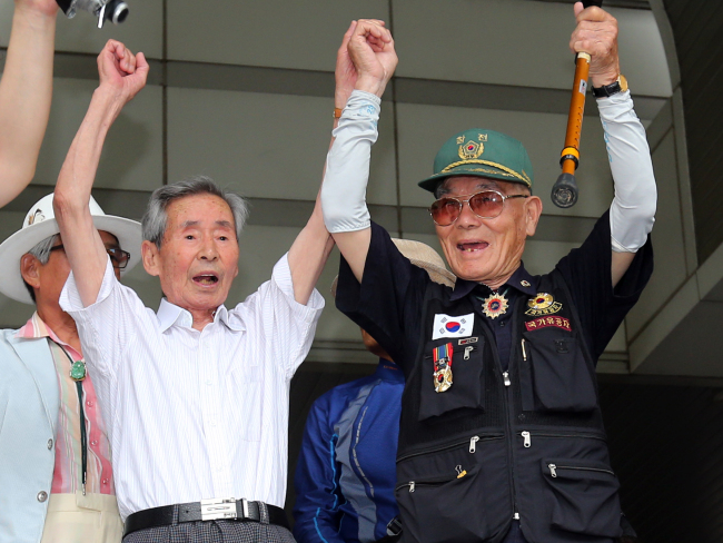 Yeo Yoon-taek (left) and Lee Choon-sik cheer at the Seoul High Court on July 10 after it ordered Nippon Steel and Sumitomo Metal to pay them compensation for forced labor during Japan’s colonization of Korea. (Yonhap News)