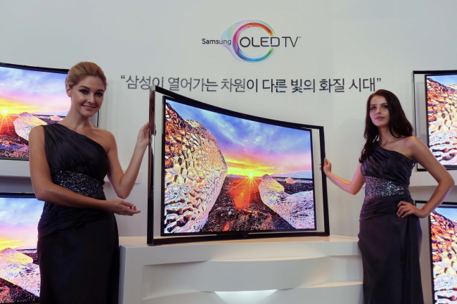 Models pose with Samsung’s curved OLED TVs (bottom) and LG’s Utra HD TVs (top). ( Samsung Electronics, LG Electronics)