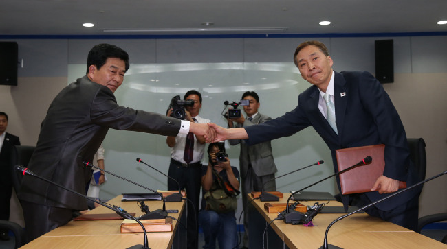South Korea’s lead negotiator Kim Ki-woong (right) and his North Korean counterpart Park Chol-su shake hands after signing an agreement to reopen the Gaeseong industrial park at the close of the seventh round of talks in the North’s border city on Wednesday. (Joint Press Corps)