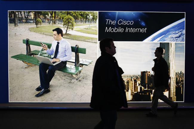 Visitors pass an illuminated Cisco Systems Inc. advertisement at the Mobile World Congress in Barcelona. (Bloomberg)