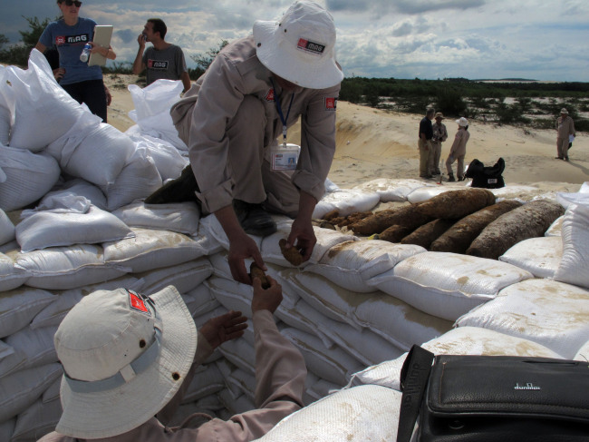 A Vietnamese deminer hands unexploded ordinance to a colleague ahead of a controlled detonation in Vinh Thai, Vietnam. (AP-Yonhap News)