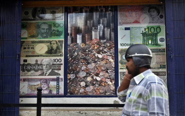 A man on his mobile phone outside a currency exchange shop in Bangalore, India, Tuesday. (AP-Yonhap News)