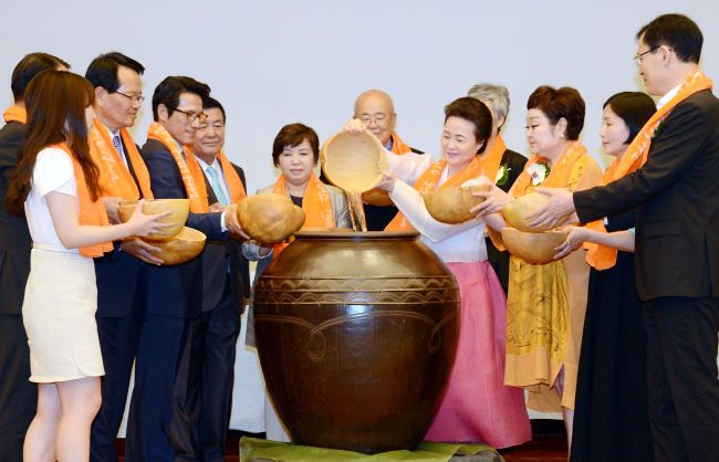 Supporters promoting the designation of the nation’s traditional wines as UNESCO Cultural Heritage reenact the making of wine at a ceremony for the inauguration of the support group at Shinsegae Department Store in downtown Seoul on Thursday. (Ahn Hoon/The Korea Herald)