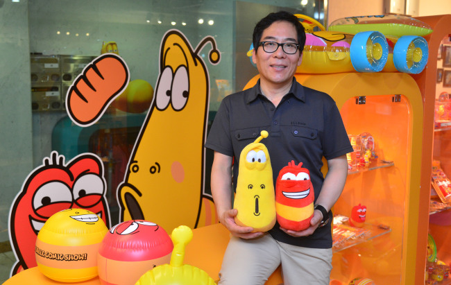 Kim Kwang-yong, CEO of TUBAn, an animation studio, poses for a photo with Larva characters in his office in Seoul on Monday. (Lee Sang-sub/The Korea Herald)