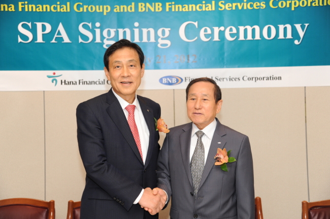 Hana Financial Group chairman Kim Jung-tai (left) poses with BNB Financial Services Corp. head Sam C. Chung after signing a pact to take over the New York-based lender, whose flagship unit is Broadway National Bank, in July 2012. (Hana Financial)