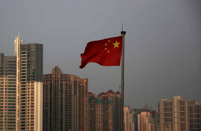 A Chinese national flag flies in front of residential buildings in the Lujiazui district of Shanghai. (Bloomberg)