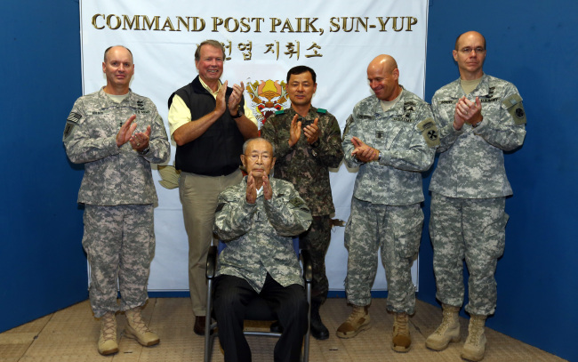 Gen. Paik Sun-yup (seated), 8th Army Deputy Commanding General for Operations Maj. Gen. Walter M. Golden Jr. (left) and others applaud during a ceremony to name Paik the honorary 8th Army commander at the New Mexico Range near Panmunjeom in Gyeonggi Province on Thursday. (Lee Sang-sub/The Korea Herald)