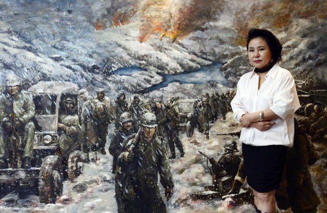 Kim Mi-jung poses next to an illustration of U.S. Marines retreating during the Battle of the Chosin Reservoir. (Park Hae-mook/The Korea Herald)