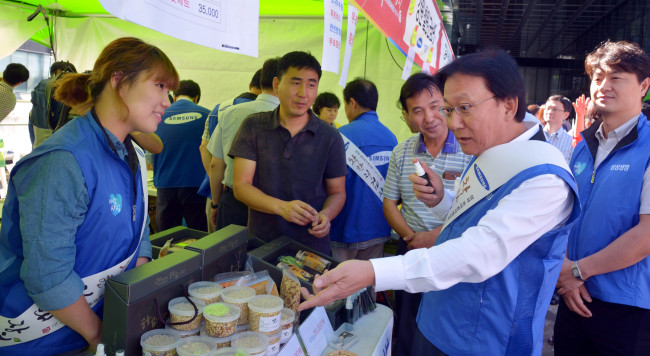 Park Keun-hee (right), vice chairman & CEO of Samsung Life Insurance, asks about agricultural products in a market at the Samsung Electronics headquarters in Seoul on Wednesday, where consumers can buy agricultural and fishery products directly from farmers and fishers. The group opened markets at 35 of its affiliates across the country. (Kim Myung-sub/The Korea Herald)