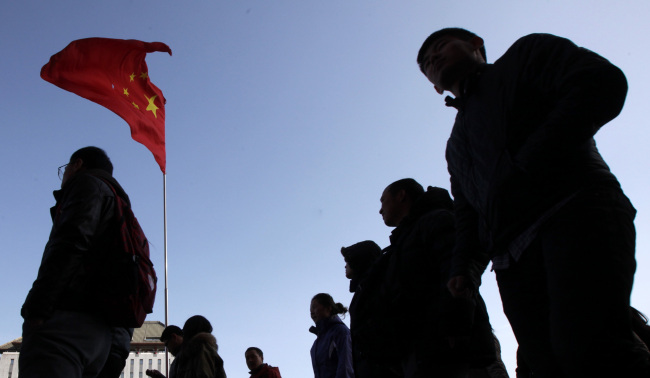 Shoppers and pedestrians walk past a Chinese national flag displayed outside a department store in Beijing. (Bloomberg)