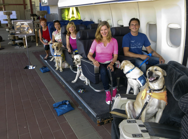 Megan Blake, Air Hollywood K9 Flight School Program Director (sitting left, front row) with dog Super Smiley (far right) and other puppies from the Canine Companions for Independence pose for a photo during a K9 flight simulation at the America’s Family Pet Expo, at the Orange County Fair Grounds in Costa Mesa, California. (AP-Yonhap News)