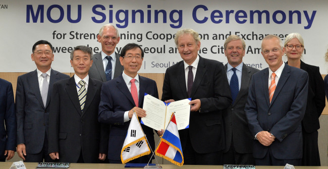 Seoul Mayor Park Won-soon (fourth from left) and his Amsterdam counterpart Eberhard van der Laan (fourth from right) pose at City Hall on Monday after signing a memorandum of understanding, promising to tighten cooperation and share policies in diverse fields including culture, transportation and water management. (Lee Sang-sub/The Korea Herald)