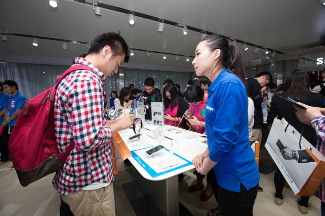 A Chinese visitor looks at Samsung’s Galaxy Note 3 and Gear at the company’s media event in Beijing on Monday. (Samsung Electronics)