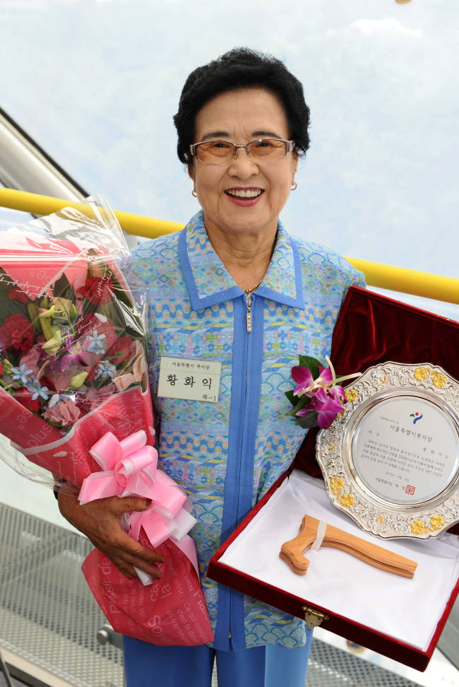 Hwang Hwa-ick poses with a bouquet and the welfare award she received from Seoul Metropolitan Government at City Hall on Sept. 9. (Seoul Metropolitan Government)