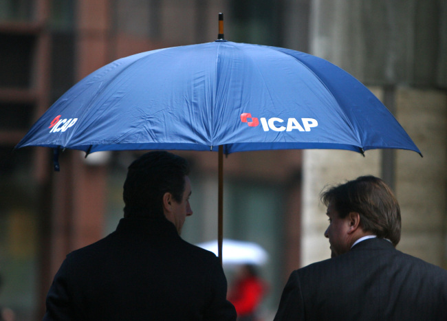 Two men shelter under an umbrella bearing the ICAP logo in London. (Bloomberg)