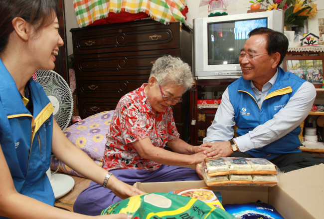 Shinhan Financial Group chairman Han Dong-woo (right) encourages an economically underprivileged elderly woman at her residence in Jongno, Seoul, Sept. 10. (Shinhan Financial Group)