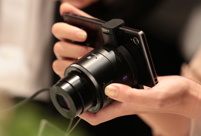 A member of the media tries out a Sony Corp. Xperia Z1 smartphone mounted with a lens-style digital camera Cyber-shot DSC-QX100 after a news conference in Tokyo on Sept. 13. (Bloomberg)