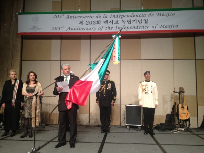 Mexican Ambassador to South Korea Jose Luis Bernal holds his nation’s flag as he delivers a speech while embassy officials look on during a reception celebrating the 203rd anniversary of Mexican Independence at a hotel in Seoul on Monday. (Philip Iglauer/The Korea Herald)