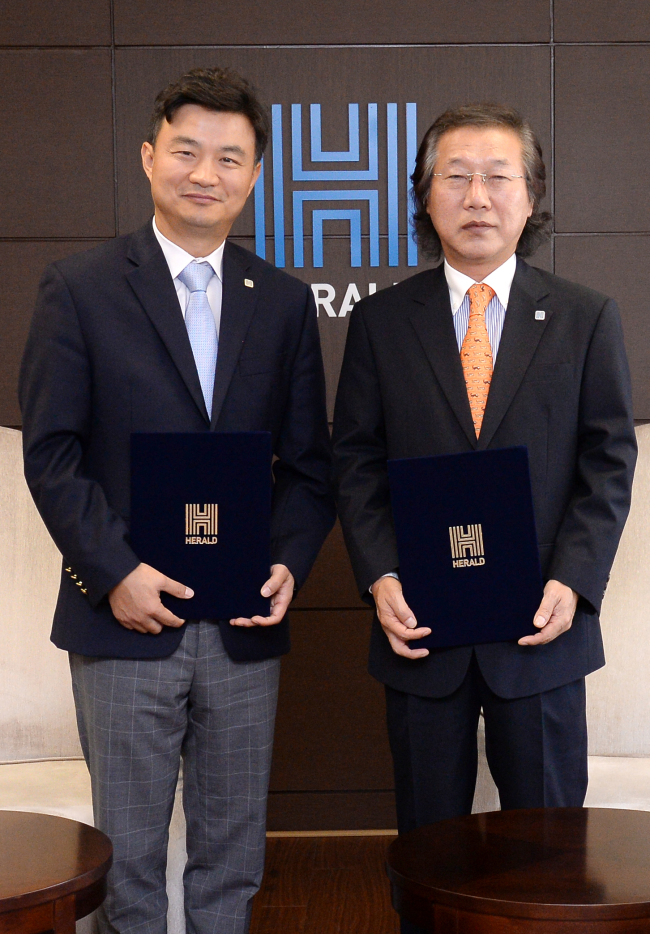 Herald Corp. CEO Lee Young-man (right) and CBNF chief Choi Jung-hwi pose after signing an agreement on Herald’s takeover of the food company at Herald Corp.’s headquarters in central Seoul last week.  (Ahn Hoon/The Korea Herald)