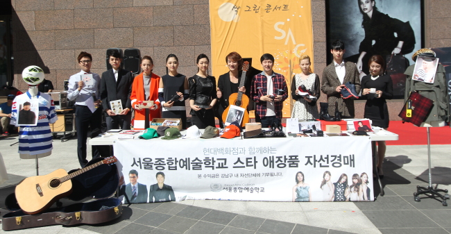 Seoul Arts College president Kim Min-sung (fourth from right) and students sell items donated by celebrities at a charity bazaar at Hyundai Department Store at COEX in Seoul on Friday. (Seoul Arts College)