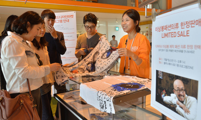 Visitors at the Herald Design Market look at a Hangeul print scarf designed by Lie Sang-bong at Blue Square in Hannam-dong, Seoul, Wednesday. (Lee Sang-sub/The Korea Herald)