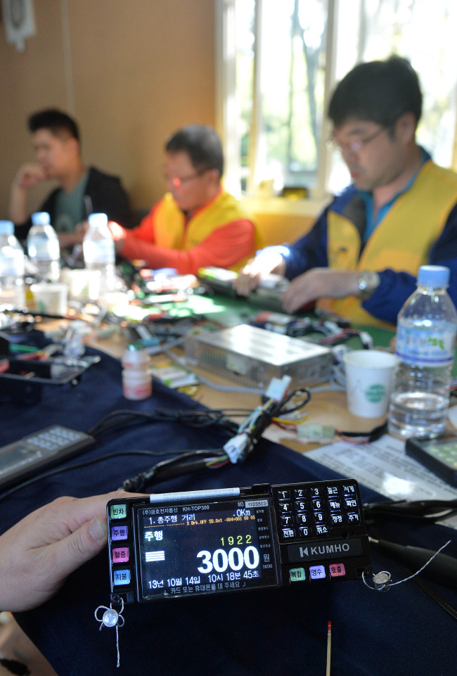 Workers reset taxi meters at a Nanjicheon Park parking lot, Seoul, Monday as a rise in basic fare in the city from 2,400 won to 3,000 won comes into force on the same day. (Lee Sang-sub/The Korea Herald)