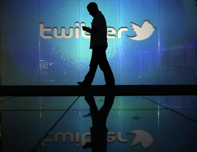 A user checks his smartphone in front of a Twitter logo in London. (Bloomberg)