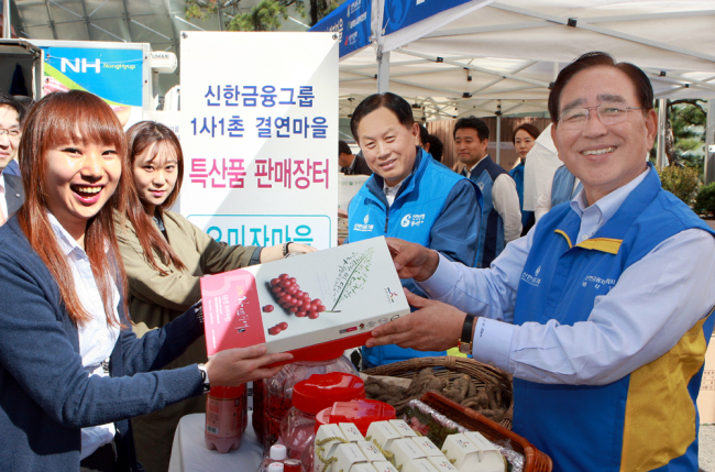 Shinhan Financial Group chairman Han Dong-woo (right) and Shinhan Bank CEO Suh Jin-won (second from right) pose during a social contribution event in which the group provided farmers with a chance to market agricultural products at its headquarters in downtown Seoul on Wednesday. (Shinhan Financial)