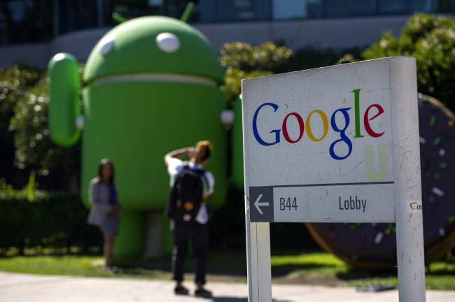 Pedestrians take photographs in front of a Google Inc. office building at the company’s headquarters in Mountain View, California. (Bloomberg)