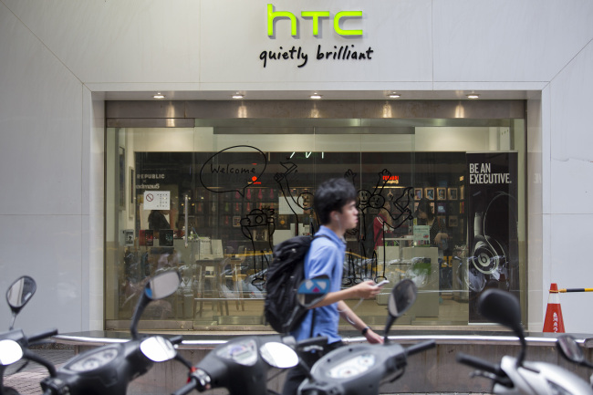 A man uses a mobile device as he walks past an HTC Corp. retail store in Taipei. (Bloomberg)