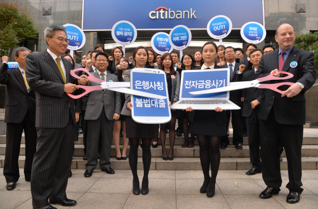 Citibank Korea CEO Ha Yung-ku (left), executives and employees attend a campaign to protect financial consumers from illegal loans and electronic financial scams, held in front of the lender’s headquarters in central Seoul on Monday. (Lee Sang-sub/The Korea Herald)