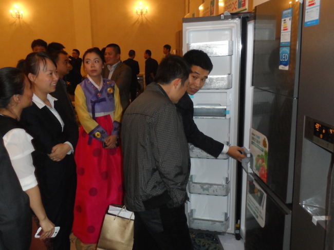 Consumers look at new home appliances from Dongbu Daewoo Electronics at an opening ceremony of the firm’s 100th store in the Chinese market in Hangzhou on Saturday. (Dongbu Group)