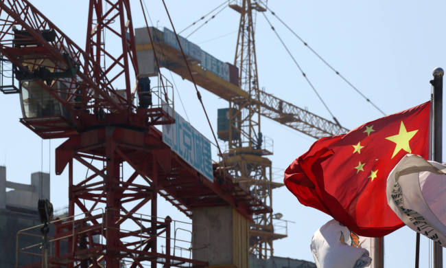 A Chinese flag flies in front of cranes at a construction site in the Fun City apartment complex in the Fangshan district of Beijing. (Bloomberg)