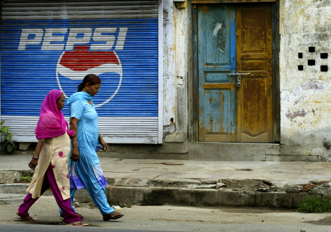 Women walk past a Pepsi advertisement in New Delhi. (Bloomberg)