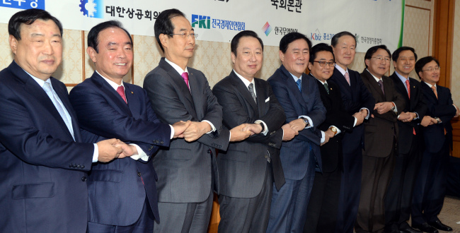 Rep. Choi Kyung-hwan (fifth from left) and Rep. Jun Byung-hun (sixth from left), floor leaders from the ruling and opposition parties, join hands with leaders from the nation’s five business associations before holding a meeting in the National Assembly on Friday. (Park Hyun-koo/The Korea Herald)