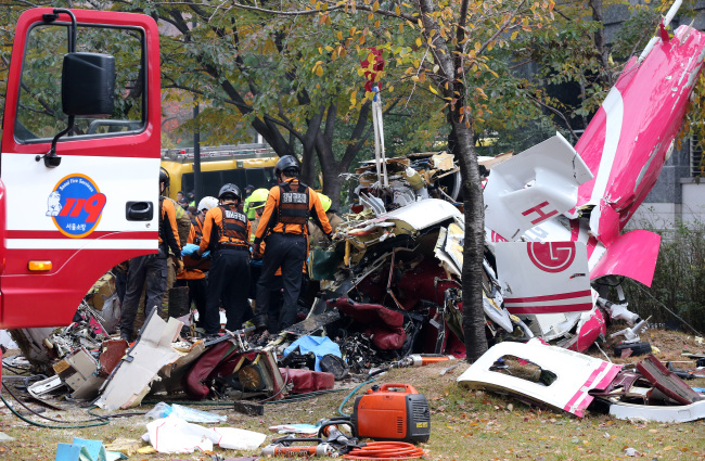 The firefighters on Saturday investigate the wreckages a site where a helicopter fell down after crashing into an apartment building in Samsung-dong, Seoul. (Yonhap News)